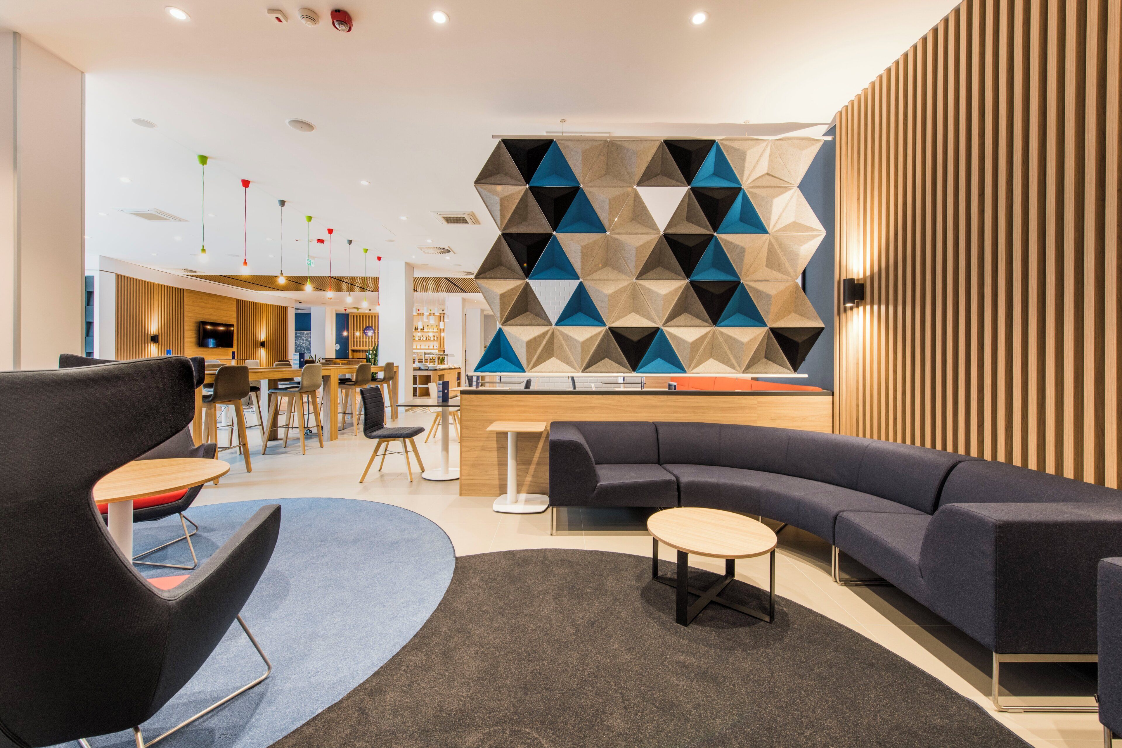 A modern lounge area with a curved sofa, a round table, and a bar area in the background.