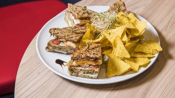 A plate with a sandwich and tortilla chips on a table.