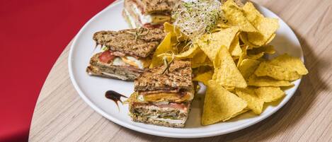 Un plato con un sándwich y totopos sobre una mesa.