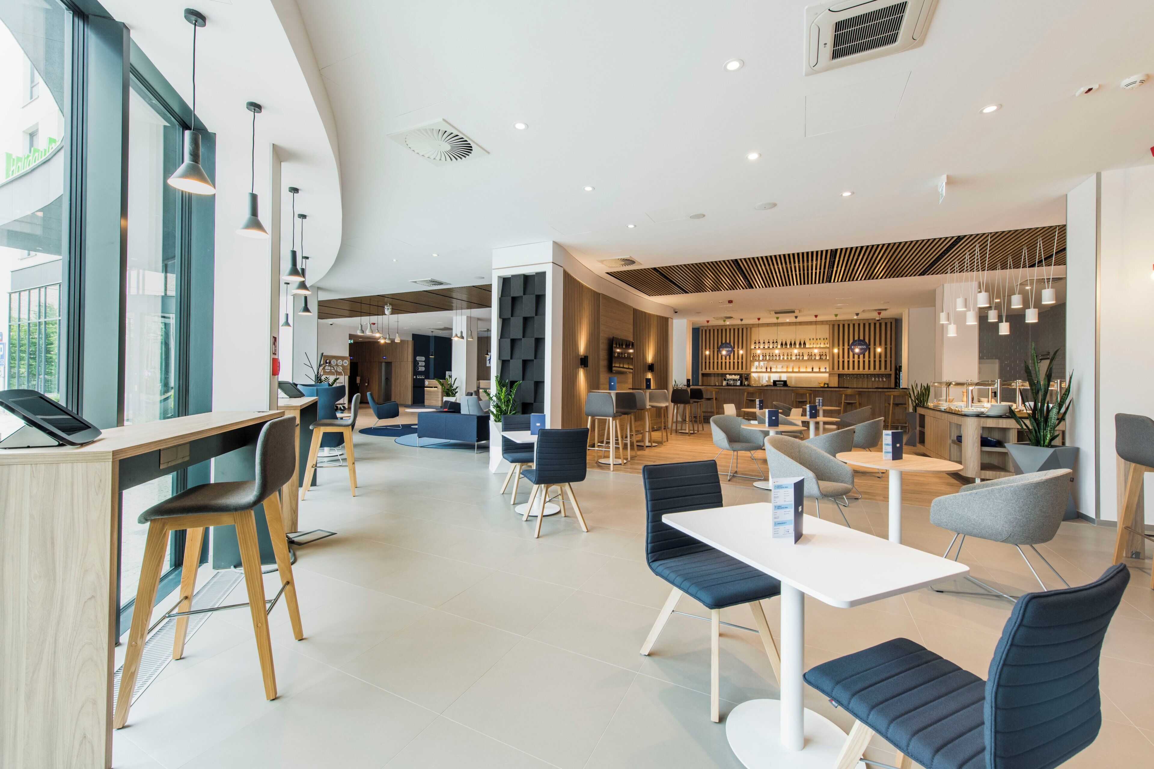 Un moderno vestíbulo de hotel con zona de bar, disposición de asientos y mostrador de recepción.