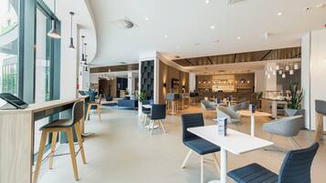 Un moderno vestíbulo de hotel con zona de bar, disposición de asientos y mostrador de recepción.