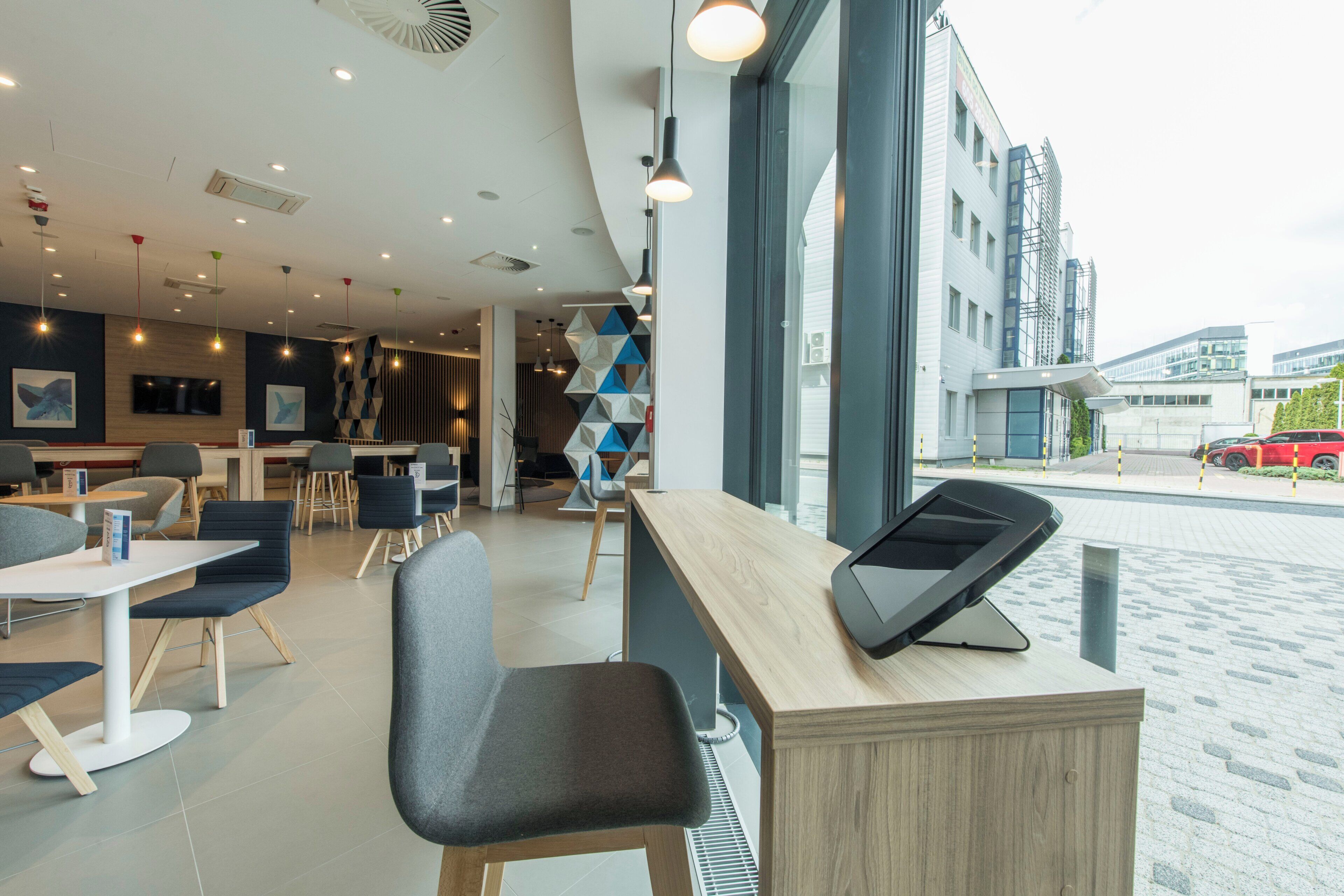 Un intérieur de restaurant moderne, avec un comptoir, un espace salon et de grandes fenêtres donnant sur une rue de la ville.