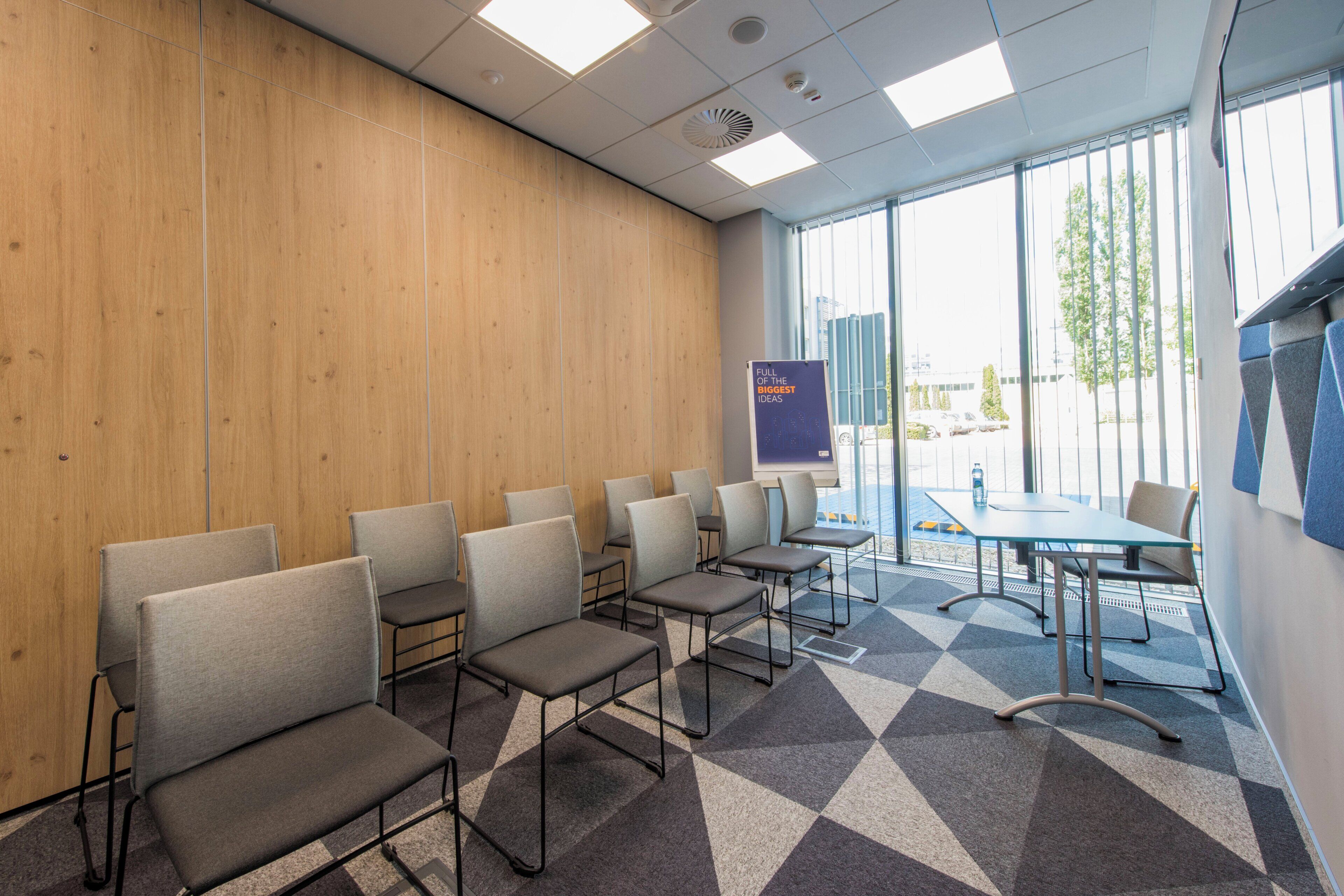 A conference room with a wooden wall, a large window, and a presentation screen.
