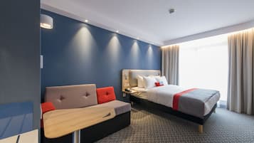A modern hotel room with a bed, a sofa, and a desk.
