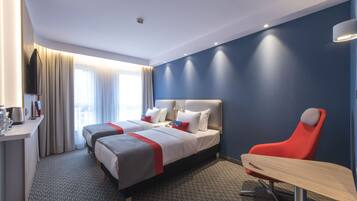 Une chambre d’hôtel avec deux lits, un bureau, une chaise et une table.