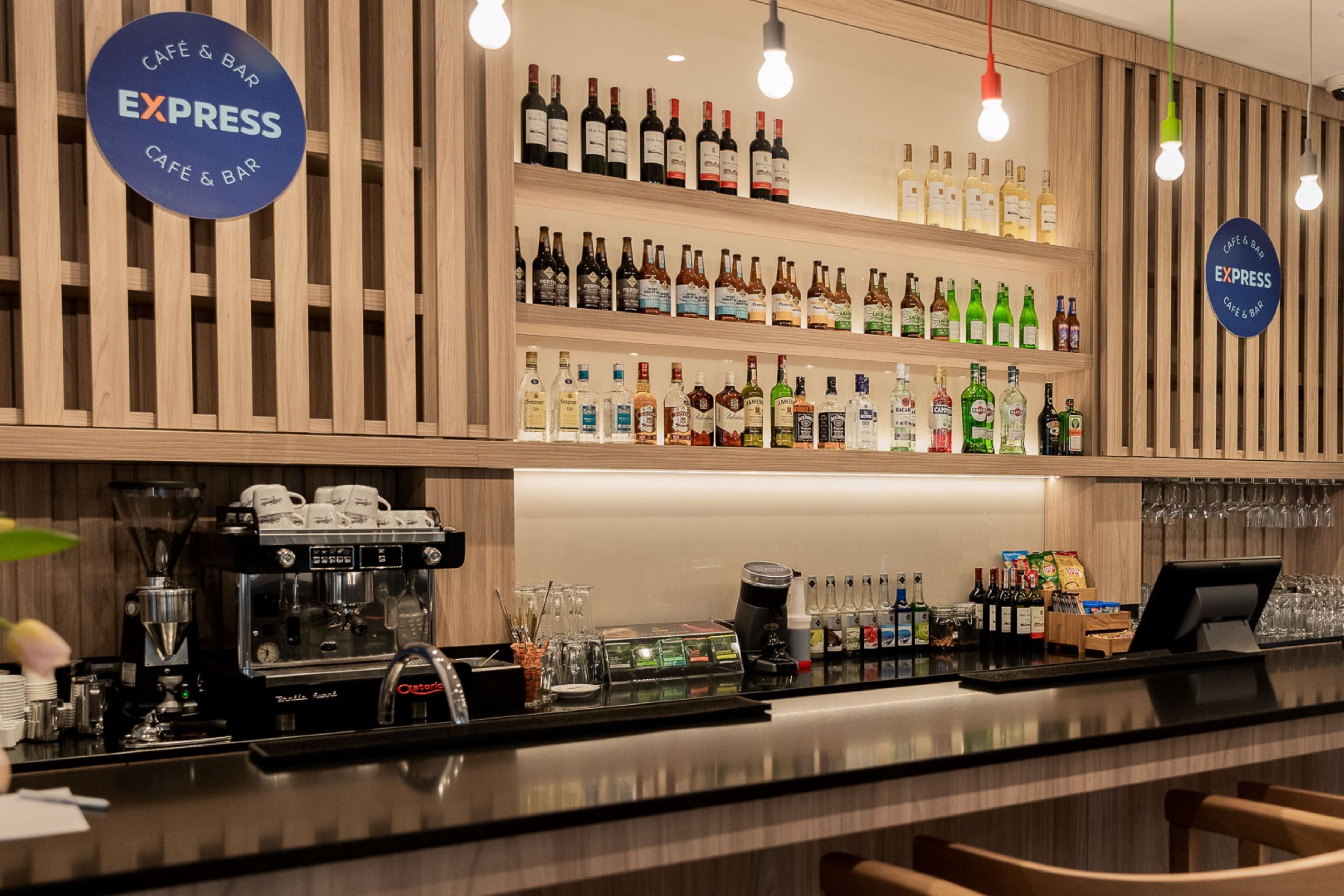 A café and bar with a wooden interior, a coffee machine, shelves of beverages, and a cash register.