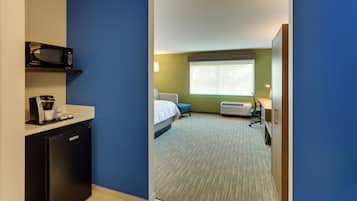 Ein Hotelzimmer mit Küchenzeile, einem Bett, einem Fenster und Teppichboden.