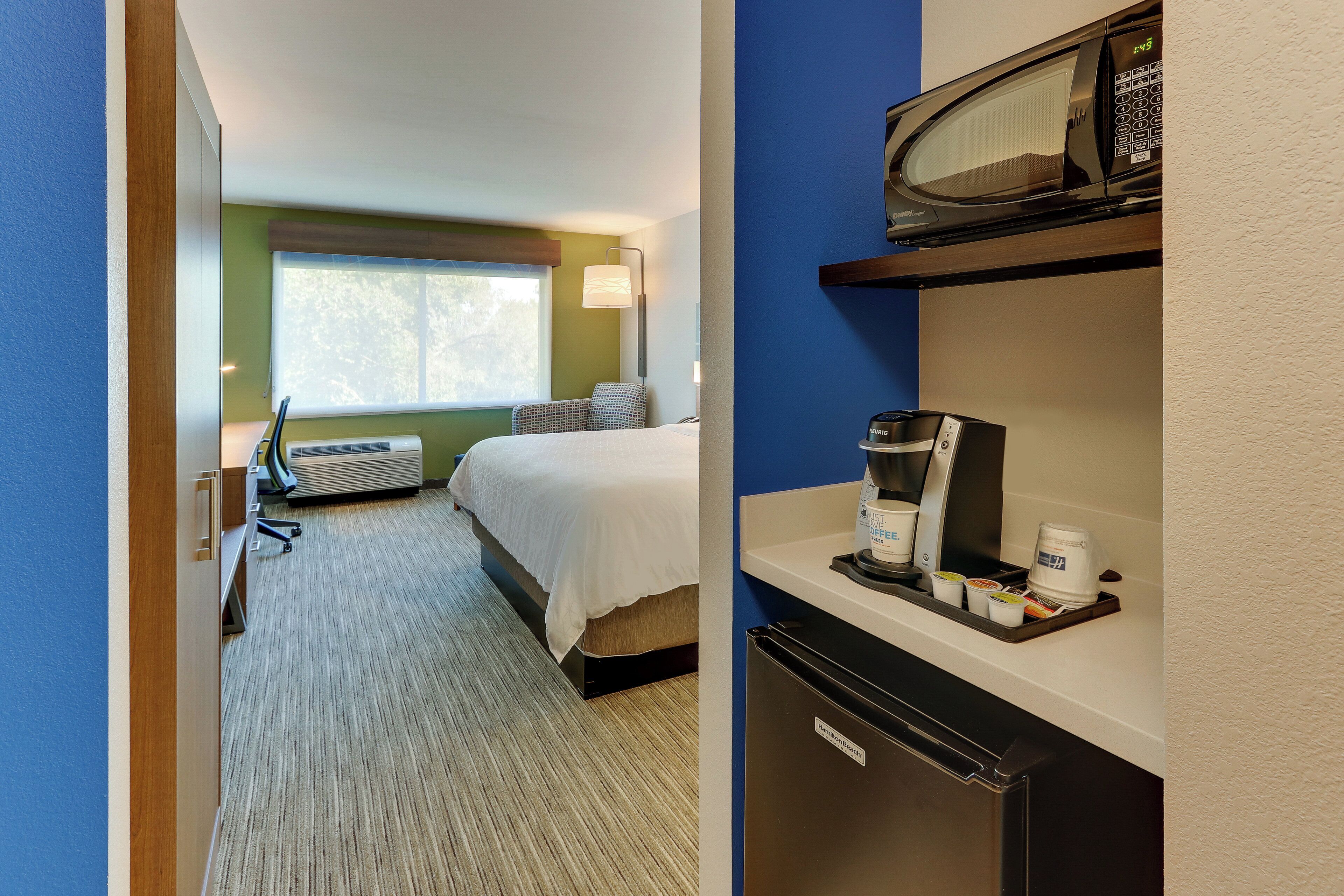 Ein Hotelzimmer mit Bett, Schreibtisch, Mikrowelle und Kaffeemaschine.