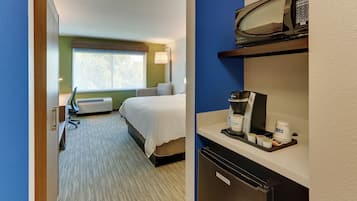 A hotel room with a bed, a desk, a microwave, and a coffee maker.