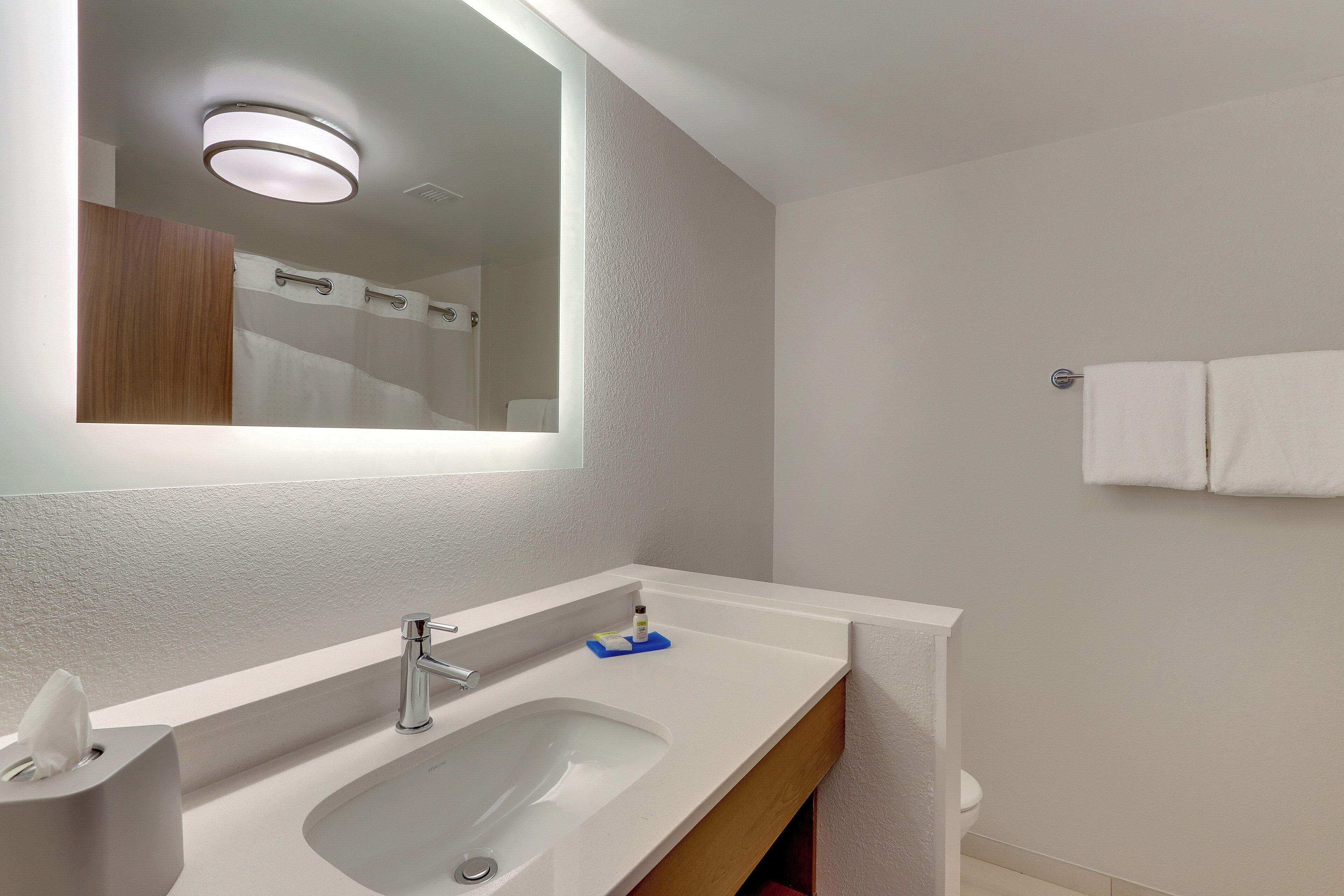 A bathroom with a white sink, mirror, and towel rack.