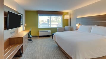 Habitación de hotel con cama, escritorio, silla, televisor, ventana y aire acondicionado.
