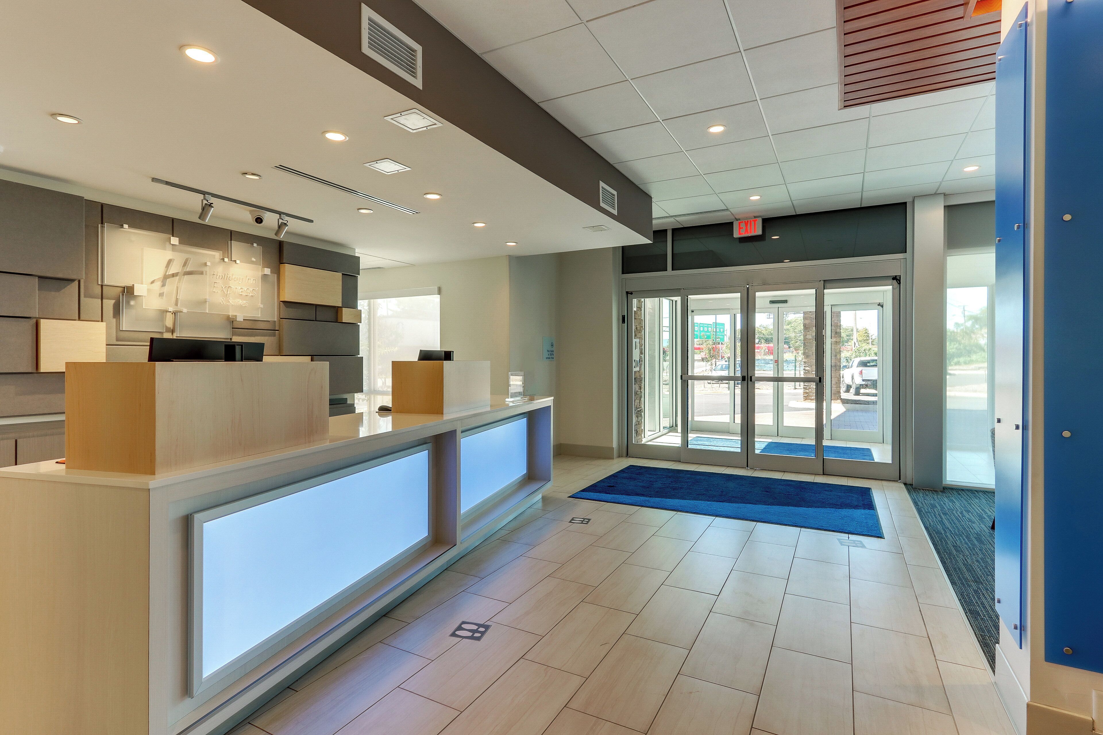 A hotel reception area with a reception desk, a digital display, and a glass door entrance.