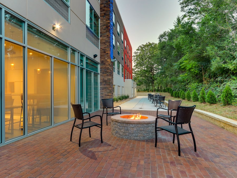 An outdoor patio with brick flooring, a fire pit, and outdoor seating.