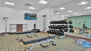 A gym with exercise equipment, a mirror, and a painting on the wall.