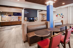 A modern cafe with a coffee station, seating area with tables and chairs, and a counter with coffee machines. - Holiday Inn Express Jacksonville South Bartram Prk by IHG (Jacksonville)