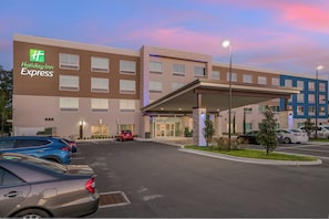 A Holiday Inn Express hotel with a parking lot, a covered entrance, and a building facade with a sign.