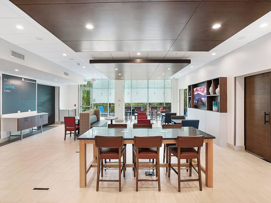 A modern conference room with a glass table, wooden chairs, and a view of the outdoors.
