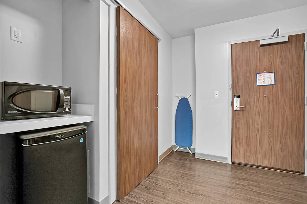 A compact kitchen with a microwave, dishwasher, and a wooden door.