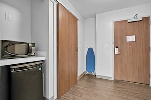 Una cocina compacta con microondas, lavavajillas y una puerta de madera.