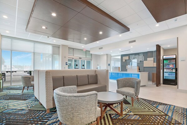 A hotel lobby with a seating area, a reception desk, and a vending machine.