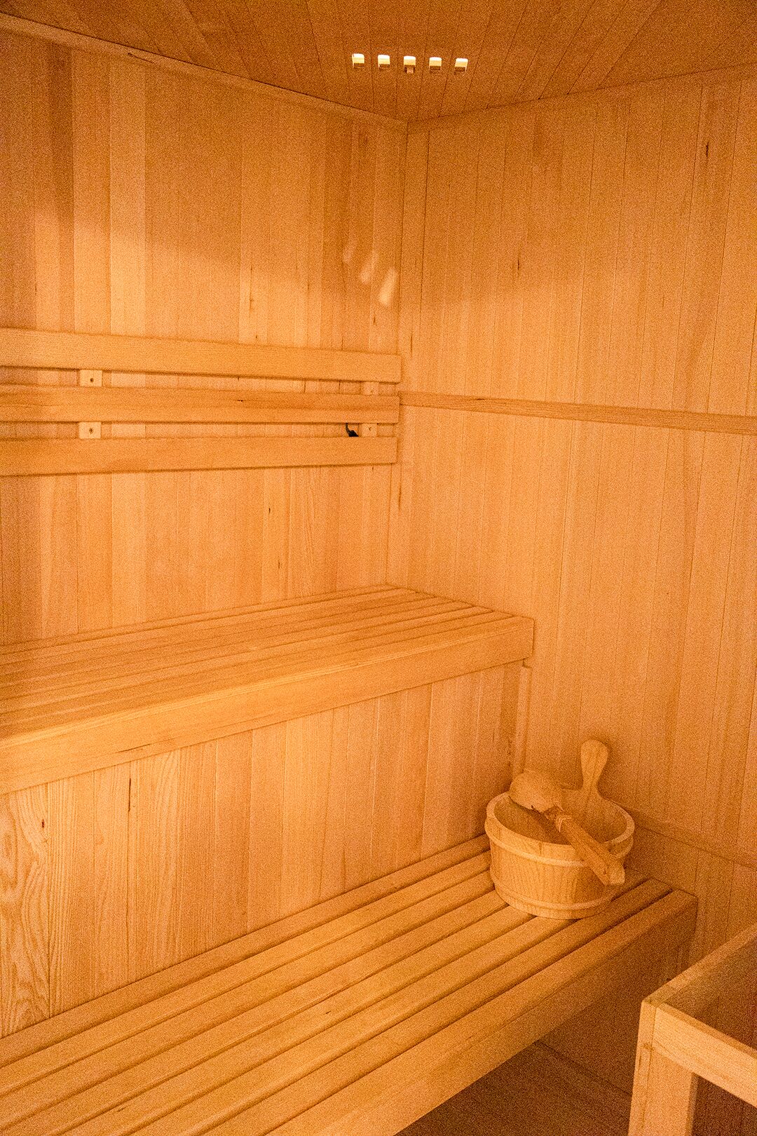 Eine Holzsauna mit Bänken und einem Holzeimer.
