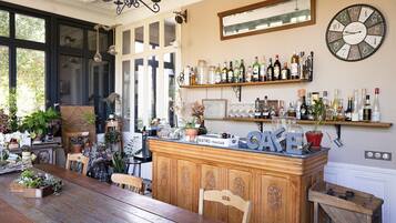 A cozy cafe with wooden furniture, a bar counter, and shelves with bottles and glasses.