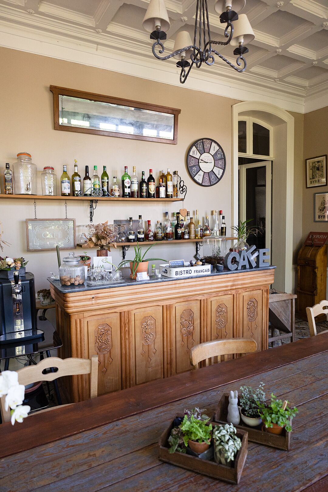 A bar area with a wooden counter, shelves with bottles, a clock, and a sign reading "BISTRO FRANCAIS".