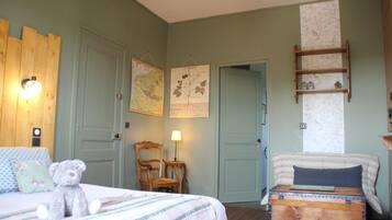 A bedroom with two beds, a wooden headboard, a map, a lamp, and a small shelf.