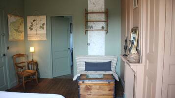 A room with a bed, a chair, a dresser, a map, and a mirror.