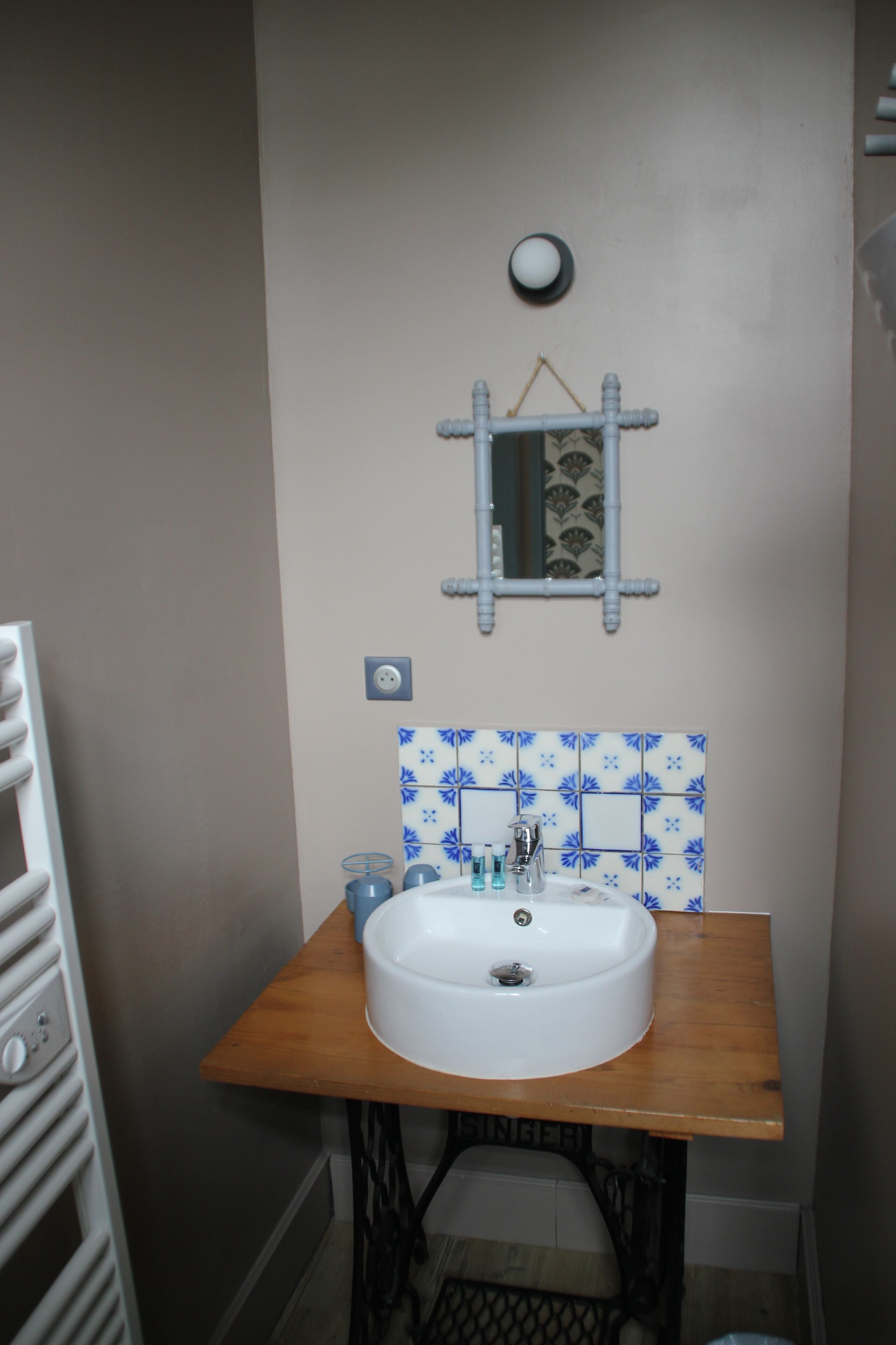 Un baño con un lavamanos blanco, un espejo y un salpicadero de azulejos con estampado azul.