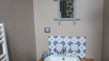 Un baño con un lavamanos blanco, un espejo y un salpicadero de azulejos con estampado azul.