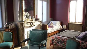 A room with a bed, a chair, a table, and a dresser.