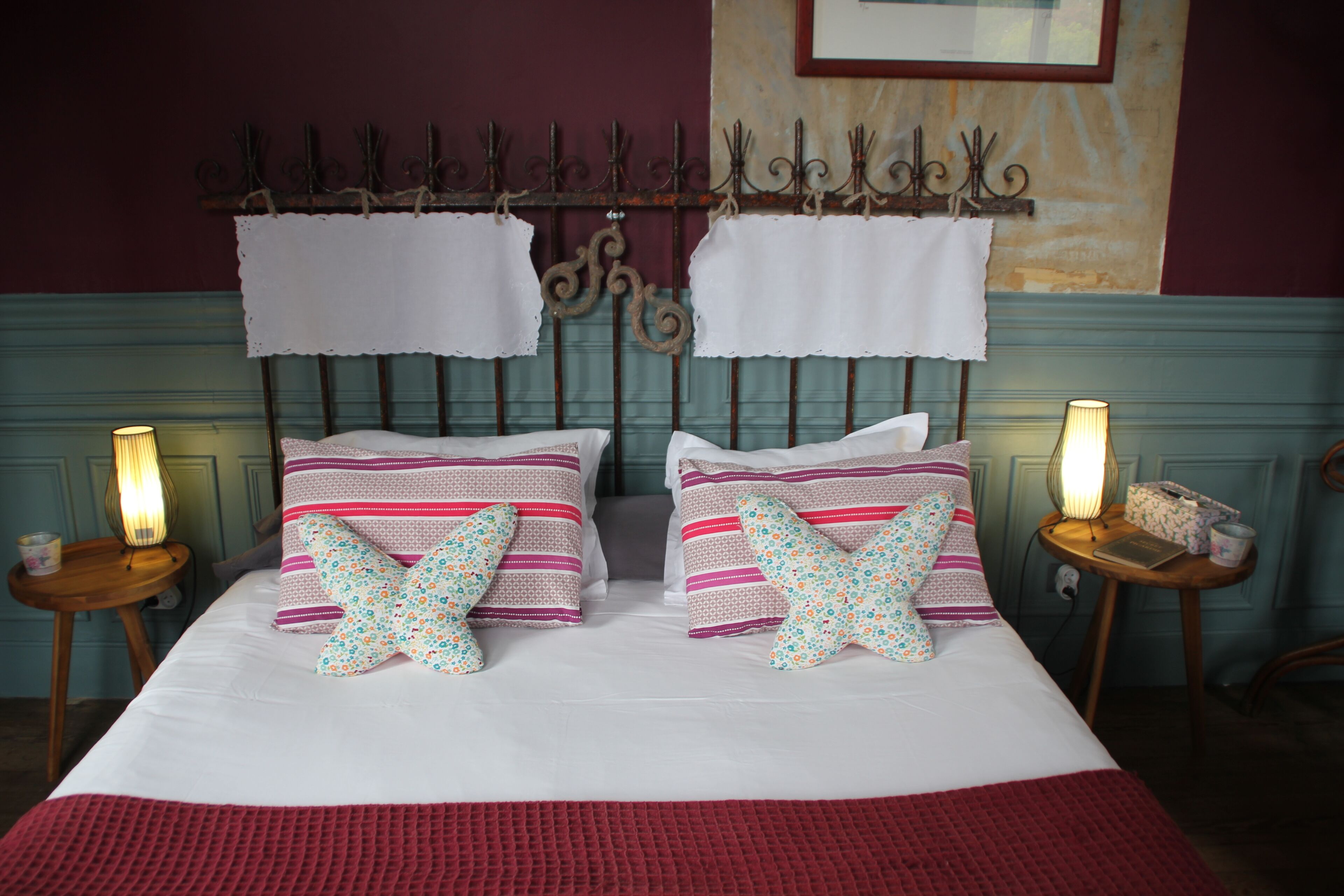A neatly made bed with striped bedding and decorative pillows, a metal headboard, and bedside lamps.