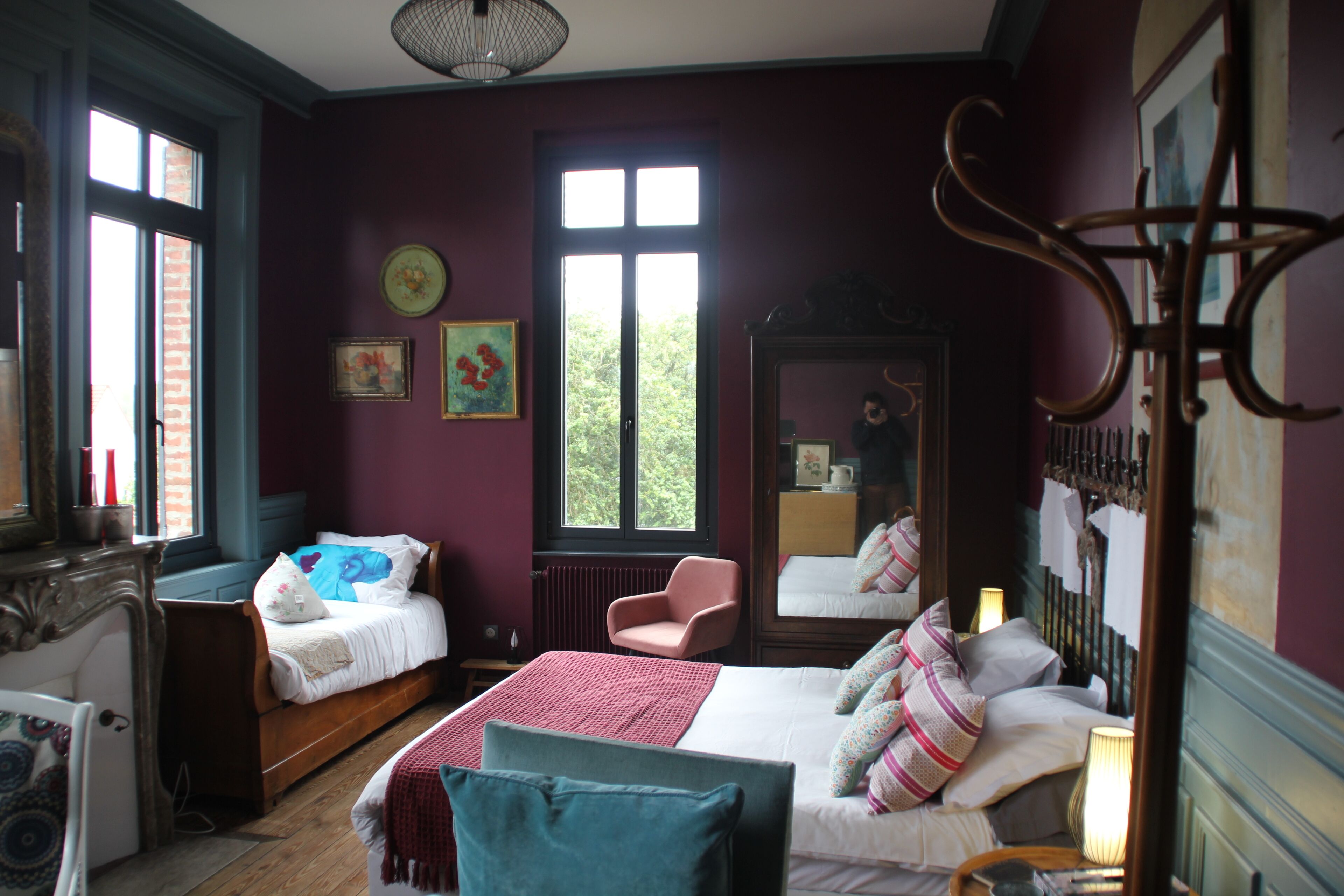 A room with two beds, a chair, a dresser, and a mirror.