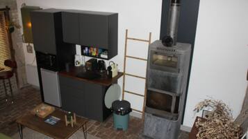 A compact kitchen with a built-in oven, a small trash bin, and a wooden table.