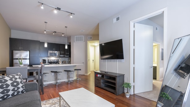Un appartement moderne comprenant une cuisine, un coin repas et un salon. Il est équipé d’un téléviseur à écran plat, d’un canapé et d’une table basse.