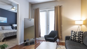 Un salon moderne avec un canapé, un fauteuil et un téléviseur à écran plat.