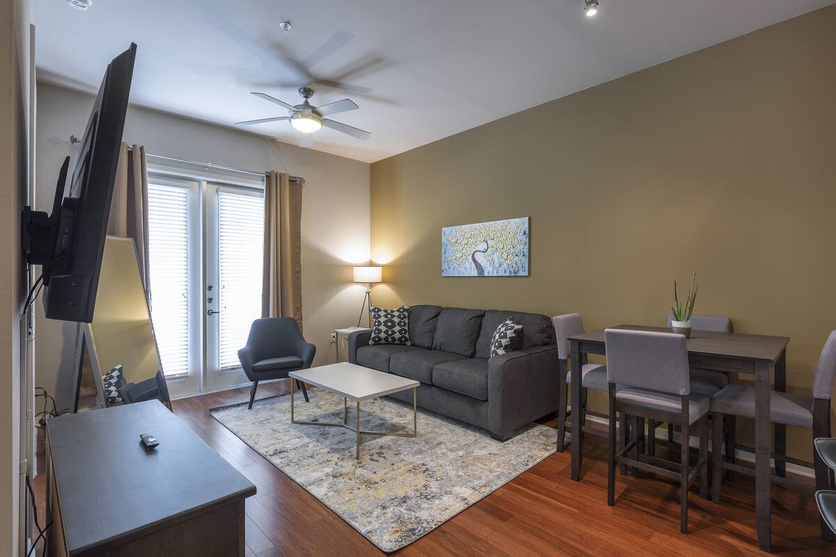 A living room with a sofa, coffee table, TV, and dining table with chairs.