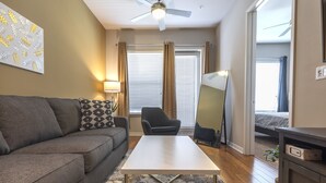 Ein modernes Wohnzimmer mit grauem Sofa, weißem Couchtisch und Deckenventilator.