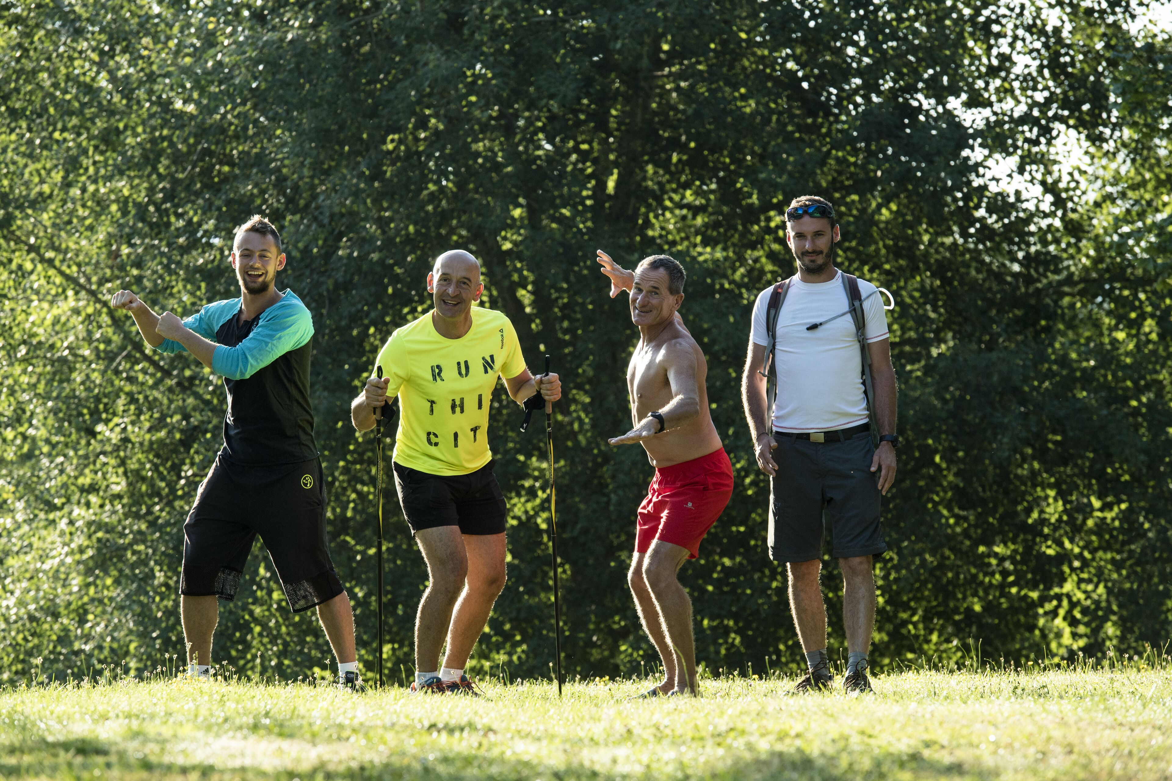 Four people standing in a grassy area with trees in the background.