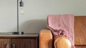 Une pièce avec un canapé en cuir marron, un meuble en bois et un tableau encadré accroché au mur.