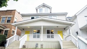 A two-story house with a front porch, two doors, and a small staircase leading to the entrance. - 2394 Indiana (SIDE) · Perfect For Groups & Families-5 Bedroom Cozy Home (Columbus)