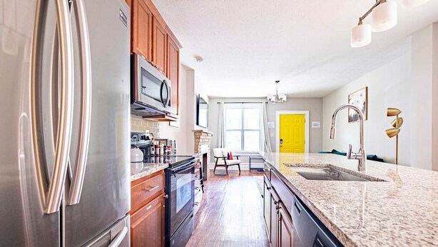 A modern kitchen with stainless steel appliances, wooden cabinets, and a granite countertop. - 2394 Indiana (SIDE) · Perfect For Groups & Families-5 Bedroom Cozy Home (Columbus)