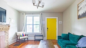 A living room with a fireplace, a sofa, a coffee table, and a yellow door. - 2394 Indiana (SIDE) · Perfect For Groups & Families-5 Bedroom Cozy Home (Columbus)