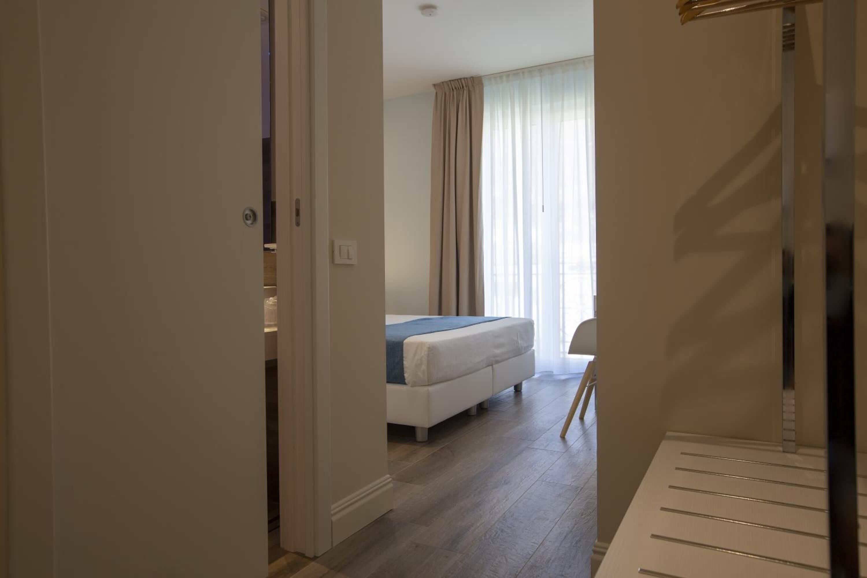 A bedroom with a bed, a chair, and a window with curtains.