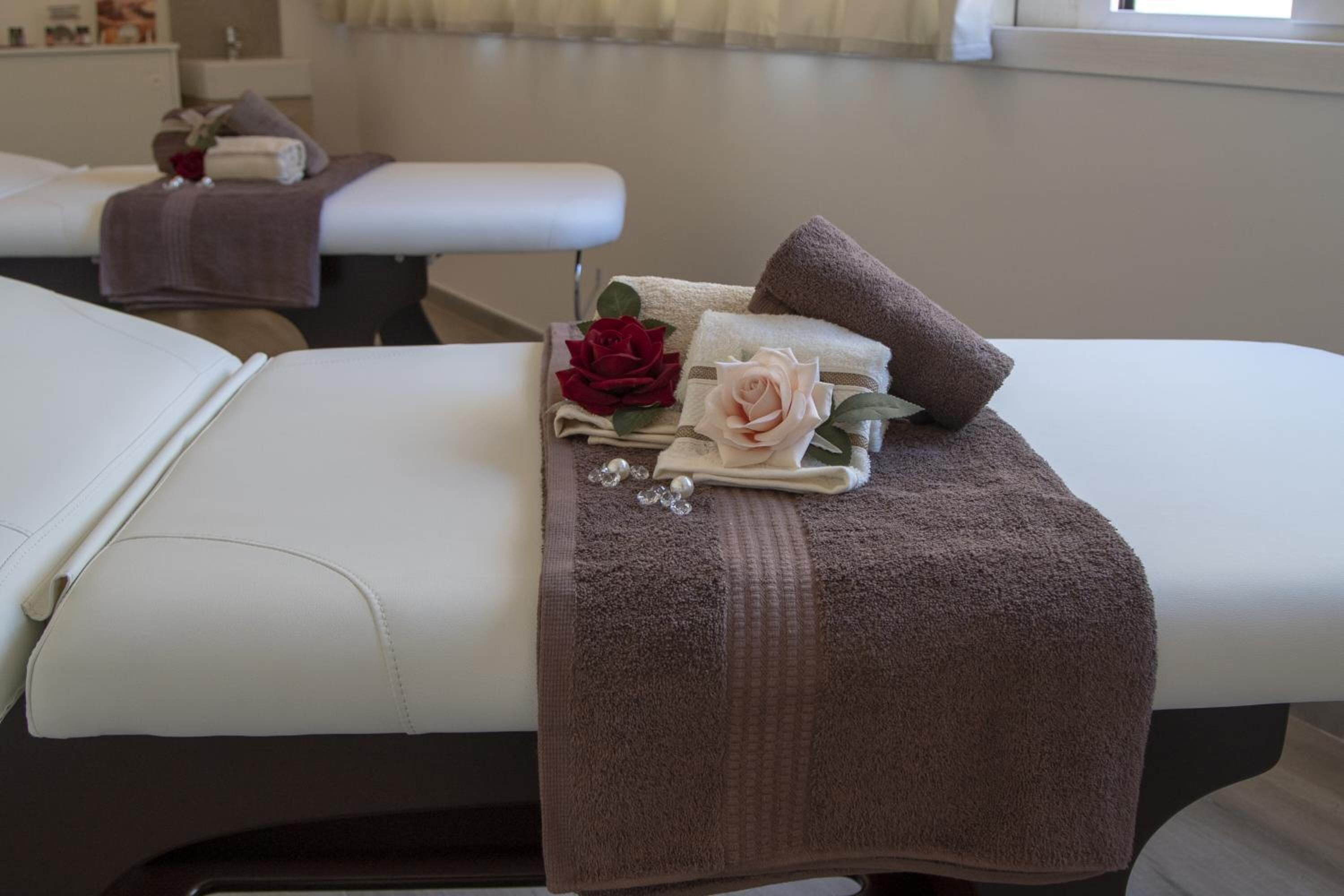 A massage table with towels, a rose, and a pearl necklace.