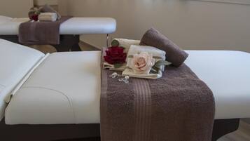 A massage table with towels, a rose, and a pearl necklace.