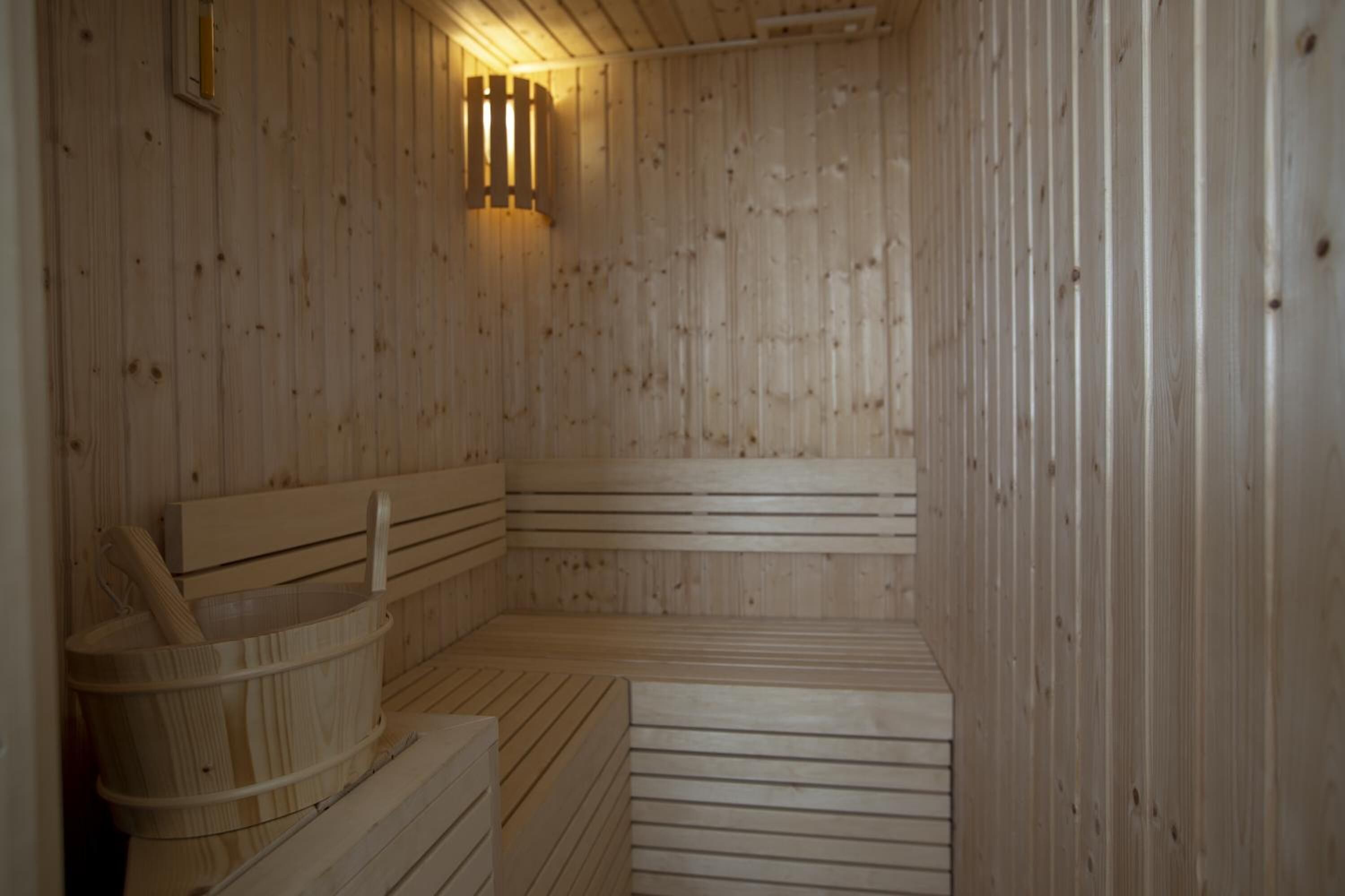 Eine Holzsauna mit Bänken und einem Holzeimer.