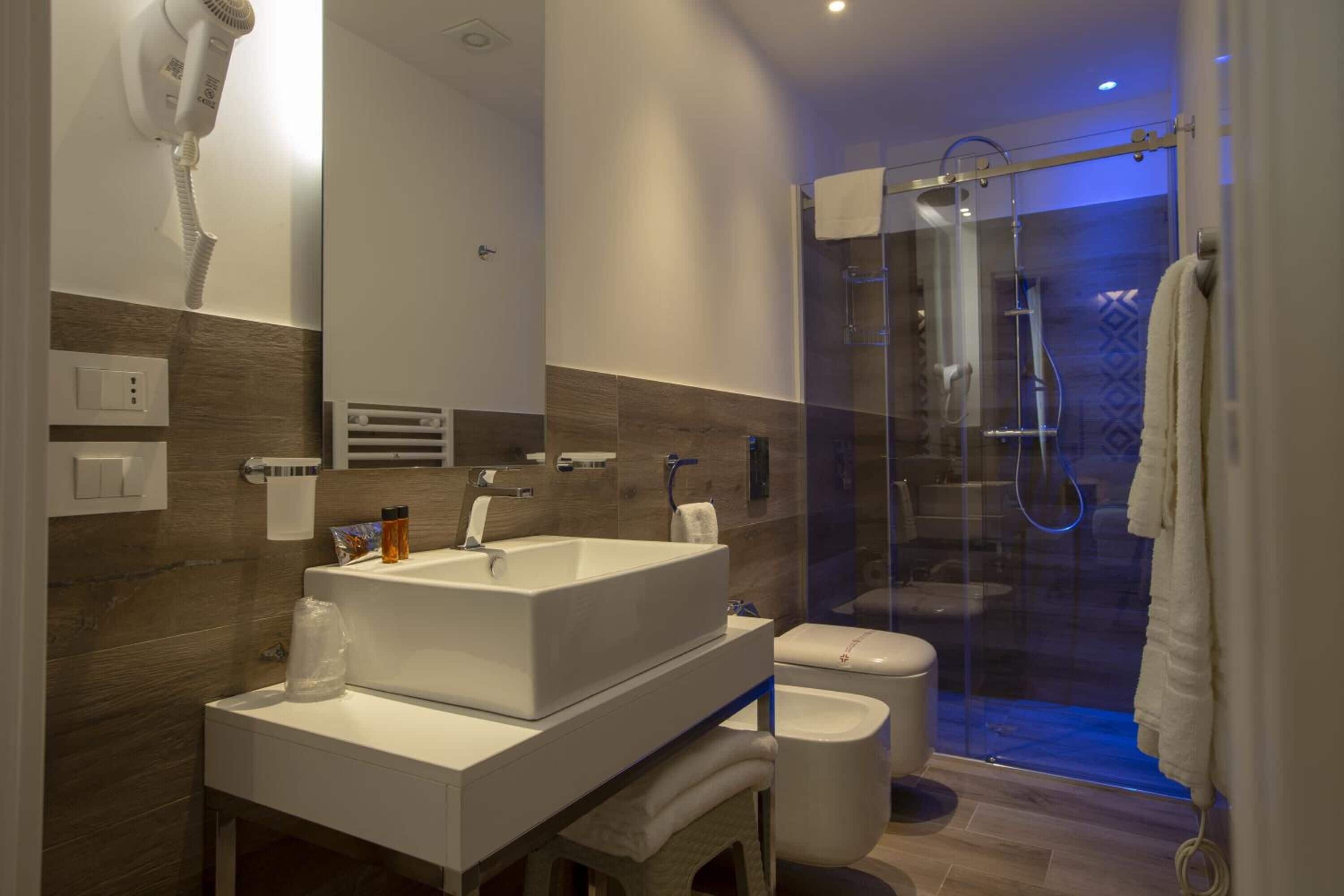 A modern bathroom with a large sink, toilet, and glass-enclosed shower.