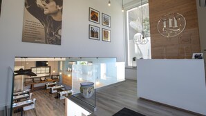 Un hall d’hôtel moderne avec un comptoir d’accueil, un espace salon et des œuvres d’art accrochées aux murs.